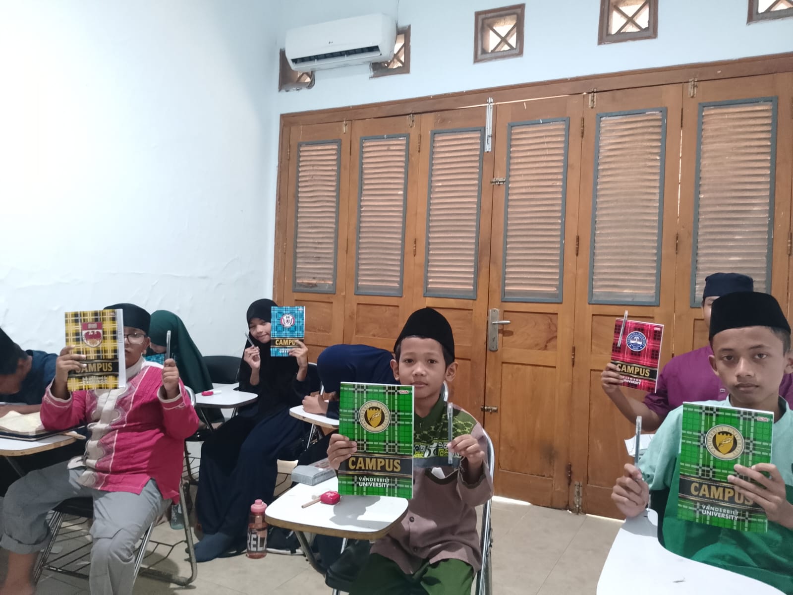 Peserta outing class Tadarus AAC sedang menunjukkan buku dan pulpen pemberian hamba Allah.